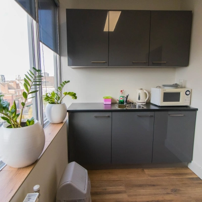 Kantoorruimte huren aan de Kaldenkerkerweg 20 in Venlo met een compacte pantry voorzien van keukenkasten, magnetron en planten voor een frisse uitstraling.