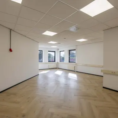 Lichte en open kantoorruimte met houten vloer en uitzicht op het Keizersveld, geschikt voor diverse werkopstellingen.