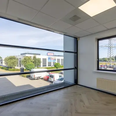 Kantoorruimte met grote ramen op Keizersveld 47 in Venray, uitzicht op parkeerplaats en naastgelegen gebouw. Perfecte plek om een kantoor te huren.