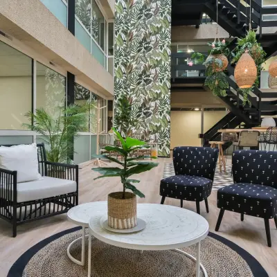 Sfeervolle ingerichte lounge in kantoorpand op Havenweg 24, Vianen Utr. Ideaal voor wie kantoorruimte wil huren. Gezellige zithoek met planten en unieke lampen in open ruimte.