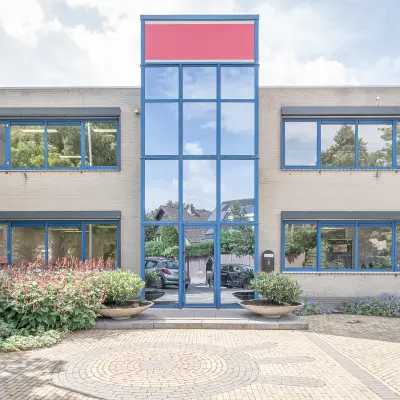 Kantoorpand op Molenweer 2 in Wateringen met moderne gevel en grote ramen, omgeven door groen. Ideaal om kantoorruimte te huren.