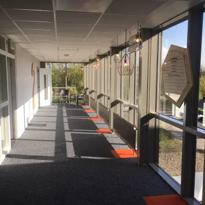 Lichte gang in een kantoorpand op Houttuinlaan 4, Woerden, met ramen aan de rechterzijde en verlichting aan het plafond.