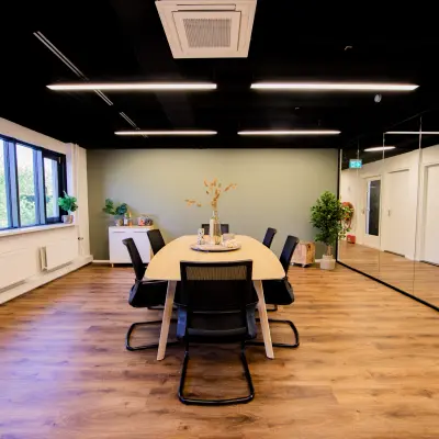 Moderne kantoorruimte op Pelmolenlaan 16, Woerden, met houten vloeren, een grote tafel en comfortabele stoelen. Ideaal voor vergaderingen of als flexibele werkruimte. Kantoorruimte huren in stijl.
