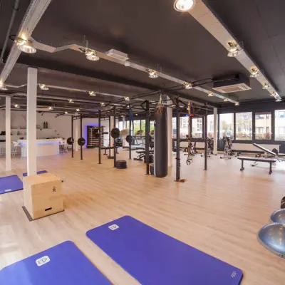 Ruime en modern ingerichte kantoorruimte op Pompmolenlaan 26, Woerden, met een open vloerplan, ideaal om kantoorruimte te huren. De ruimte is ingericht met fitnessapparatuur en lichte houten vloeren.