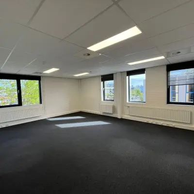 Lege kantoorruimte te huur op Pompmolenlaan 9 in Woerden, met grijze vloerbedekking, witte muren en grote ramen voor veel natuurlijk licht.