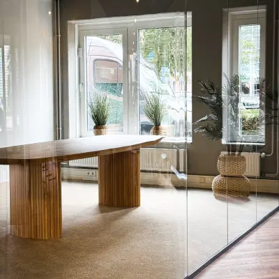 Moderne kantoorruimte in Woerden met houten tafel en glazen wanden. Grote ramen bieden veel licht. Planten zorgen voor een frisse uitstraling, ideaal voor kantoorruimte huren.