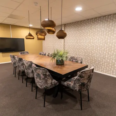 Kantoorruimte huren in Woerden op Vijzelmolenlaan 9 met een stijlvolle vergaderruimte voorzien van grote houten tafel en comfortabele stoelen, perfect voor bijeenkomsten en overleg.