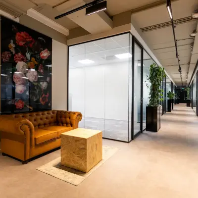Moderne kantoorgang op Boerhaavelaan 40, Zoetermeer met glazen wanden en een leren bank met kunstwerk. Ideaal voor kantoorruimte huren in een stijlvol pand.