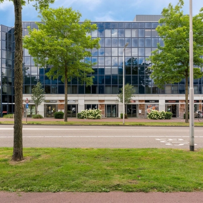 Modern kantoorpand aan Stationsplein 4 in Zwijndrecht met glazen gevel en groene omgeving, ideaal voor kantoorruimte huren.