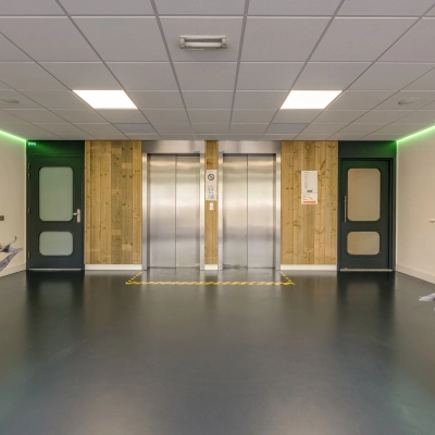 Binnenkant van het kantoorpand op Stationsplein 4 in Zwijndrecht, met een moderne lift en groene verlichting, ideaal voor wie kantoorruimte wil huren.