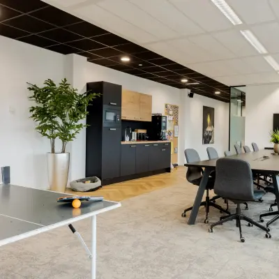 Interieur van een moderne kantoorruimte in Zwolle, Zuiderzeelaan 15-25, met tafeltennistafel, lange vergadertafel en keukenfaciliteiten. Ideaal voor het huren van een veelzijdig en productief kantoorpand.