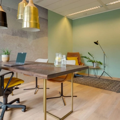 Moderne kantoorruimte huren op Zwartewaterallee 48 in Zwolle met stijlvol meubilair, vergadertafel en stoelen, groene planten en speelse verlichting.